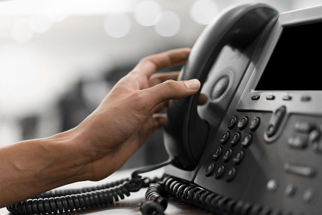 Gros plan d’un infirmier tendant la main vers un téléphone de bureau.